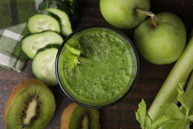 Tasty green smoothie in glass and products on wooden table, flat lay