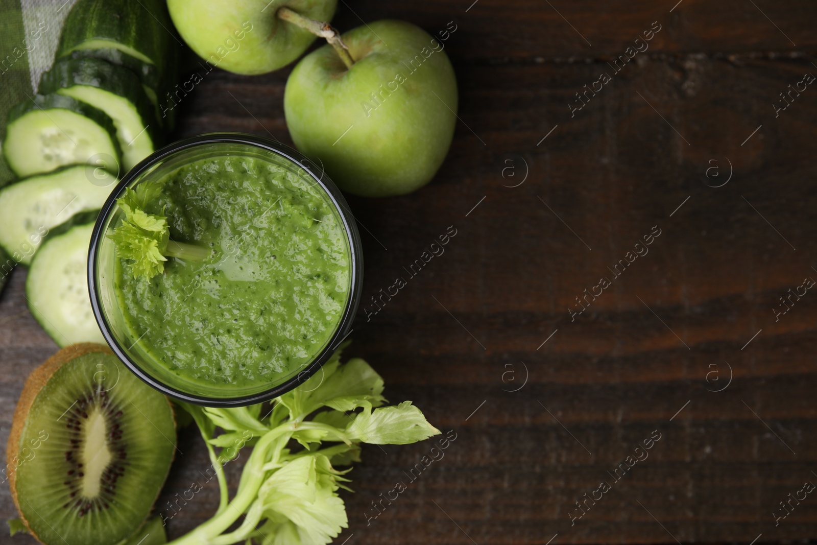 Photo of Tasty green smoothie in glass and products on wooden table, flat lay. Space for text