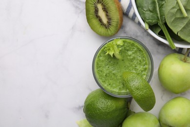 Photo of Tasty green smoothie in glass with lime and products on white marble table, flat lay. Space for text