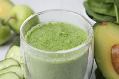 Tasty green smoothie in glass and products on table, closeup