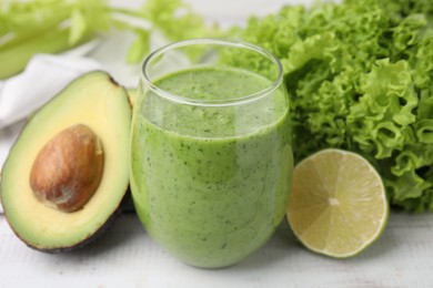 Photo of Tasty green smoothie in glass and products on wooden rustic table, closeup