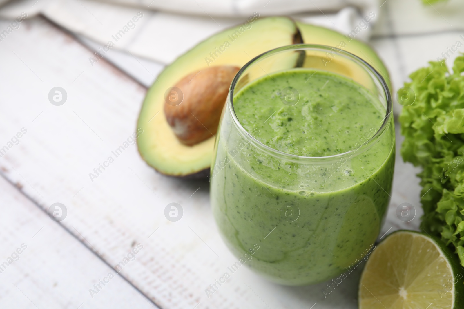 Photo of Tasty green smoothie in glass and products on wooden rustic table, closeup. Space for text