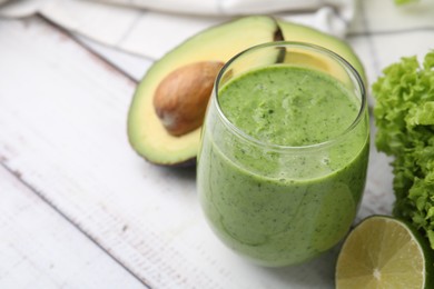 Photo of Tasty green smoothie in glass and products on wooden rustic table, closeup. Space for text