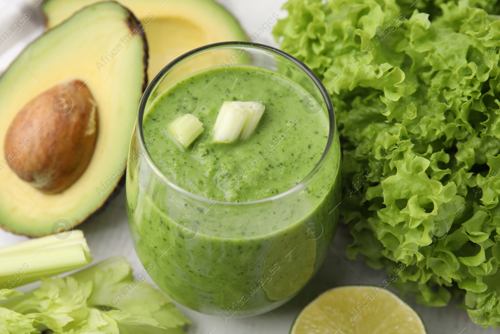 Photo of Tasty green smoothie in glass and products on white table, closeup