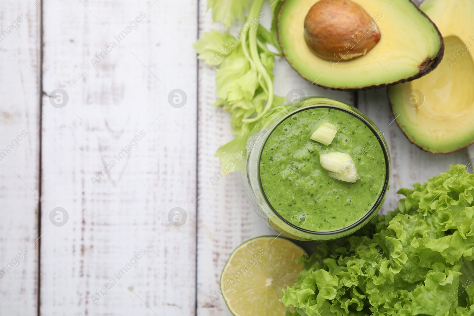 Photo of Tasty green smoothie in glass and products on wooden rustic table, flat lay. Space for text