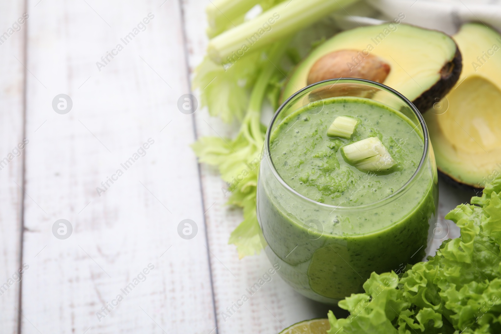 Photo of Tasty green smoothie in glass and products on wooden rustic table, closeup. Space for text