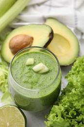 Photo of Tasty green smoothie in glass and products on white table, closeup