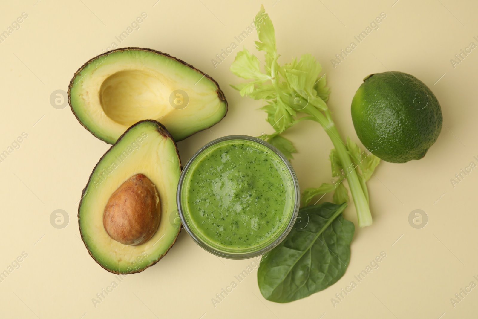 Photo of Tasty green smoothie in glass and products on beige background, flat lay