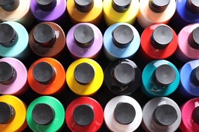 Acrylic paints of different colors in bottles on table, top view