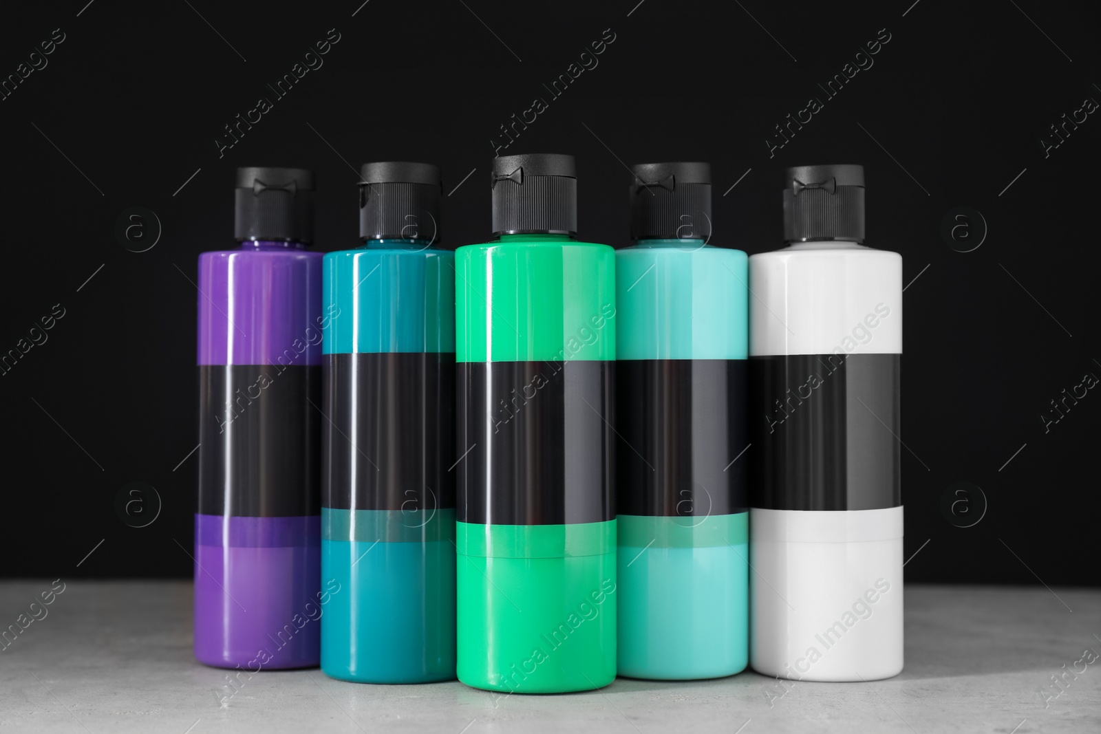 Photo of Acrylic paints of different colors in bottles on light table