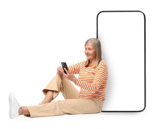 Happy mature woman holding mobile phone and sitting near big smartphone on white background