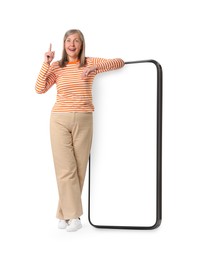 Image of Happy mature woman leaning on big mobile phone against white background