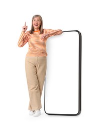 Happy mature woman leaning on big mobile phone against white background