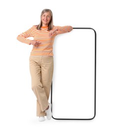 Image of Happy mature woman pointing at big mobile phone on white background