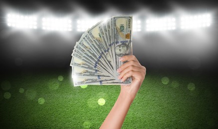 Image of Woman holding dollar bills at stadium, closeup