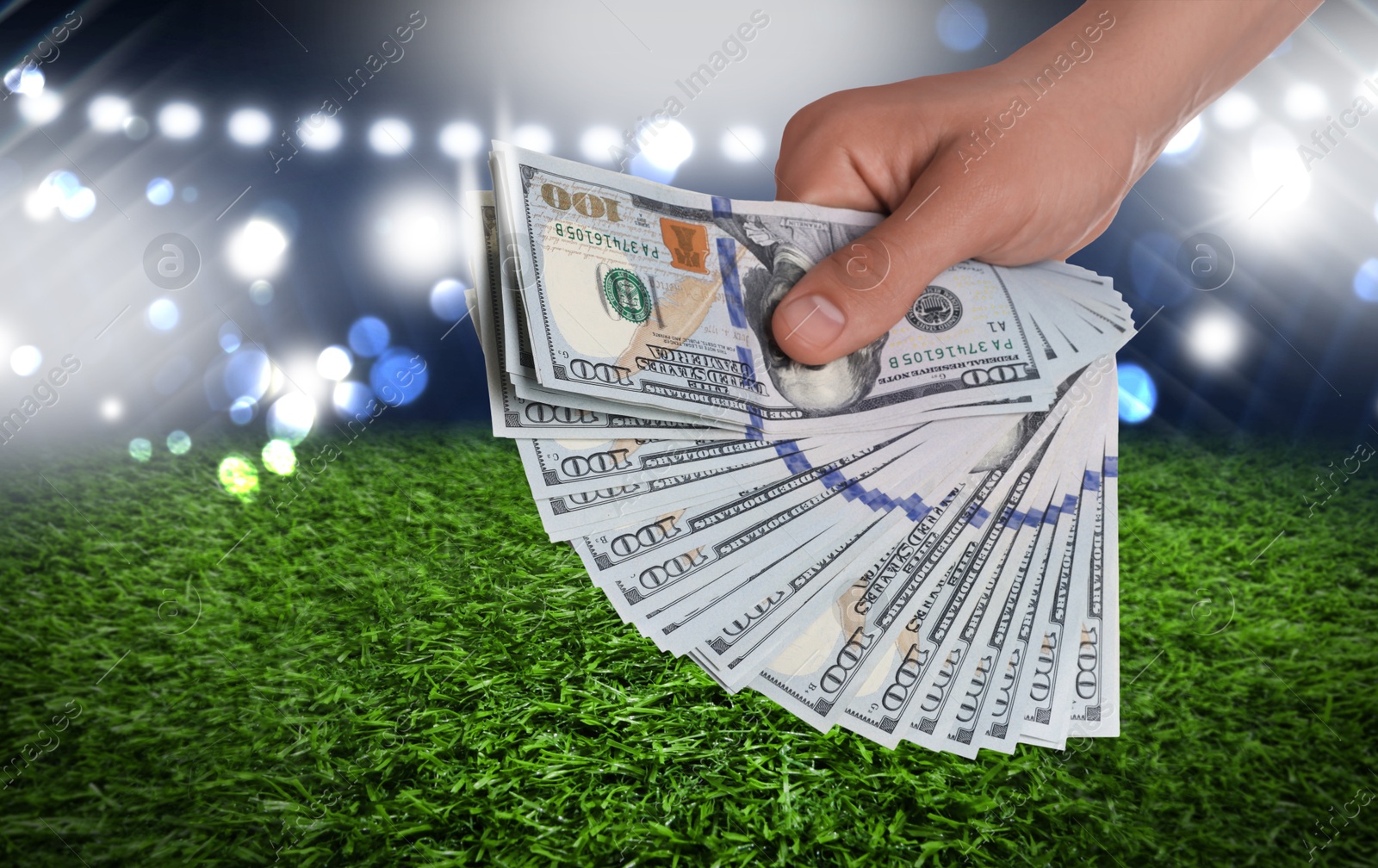 Image of Man holding dollar bills at stadium, closeup