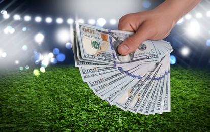 Man holding dollar bills at stadium, closeup