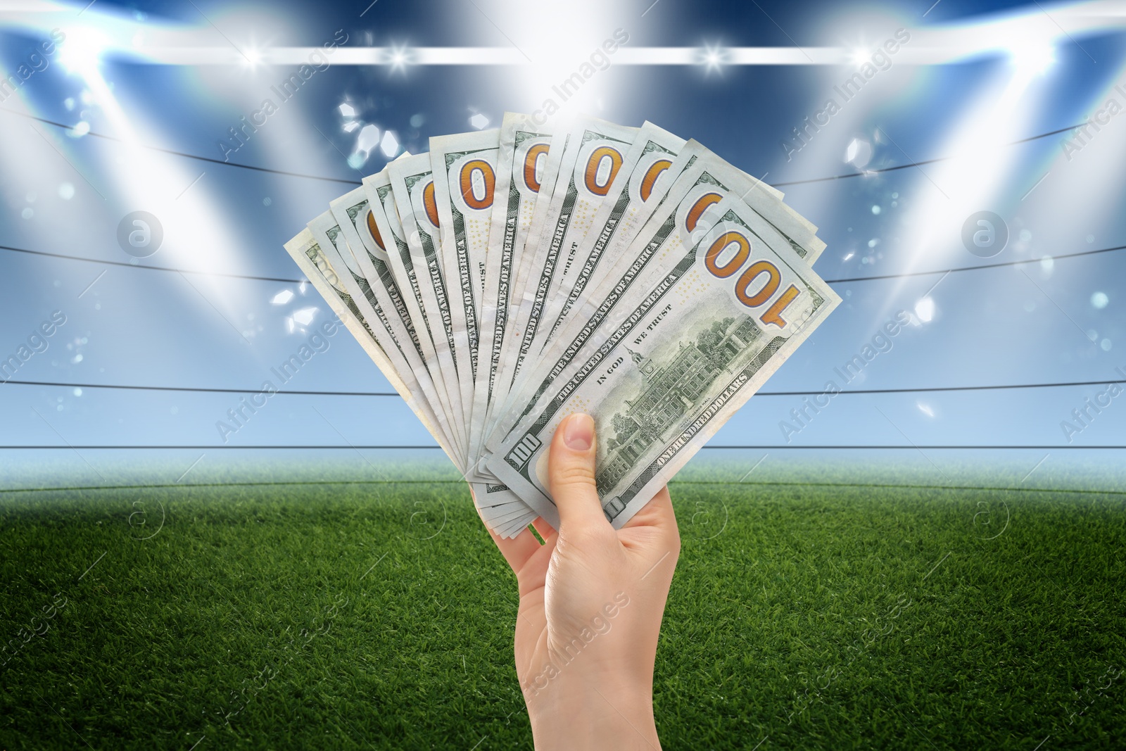 Image of Woman holding dollar bills at stadium, closeup