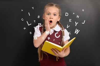 Surprised girl with book on black background. Letters flying out of book