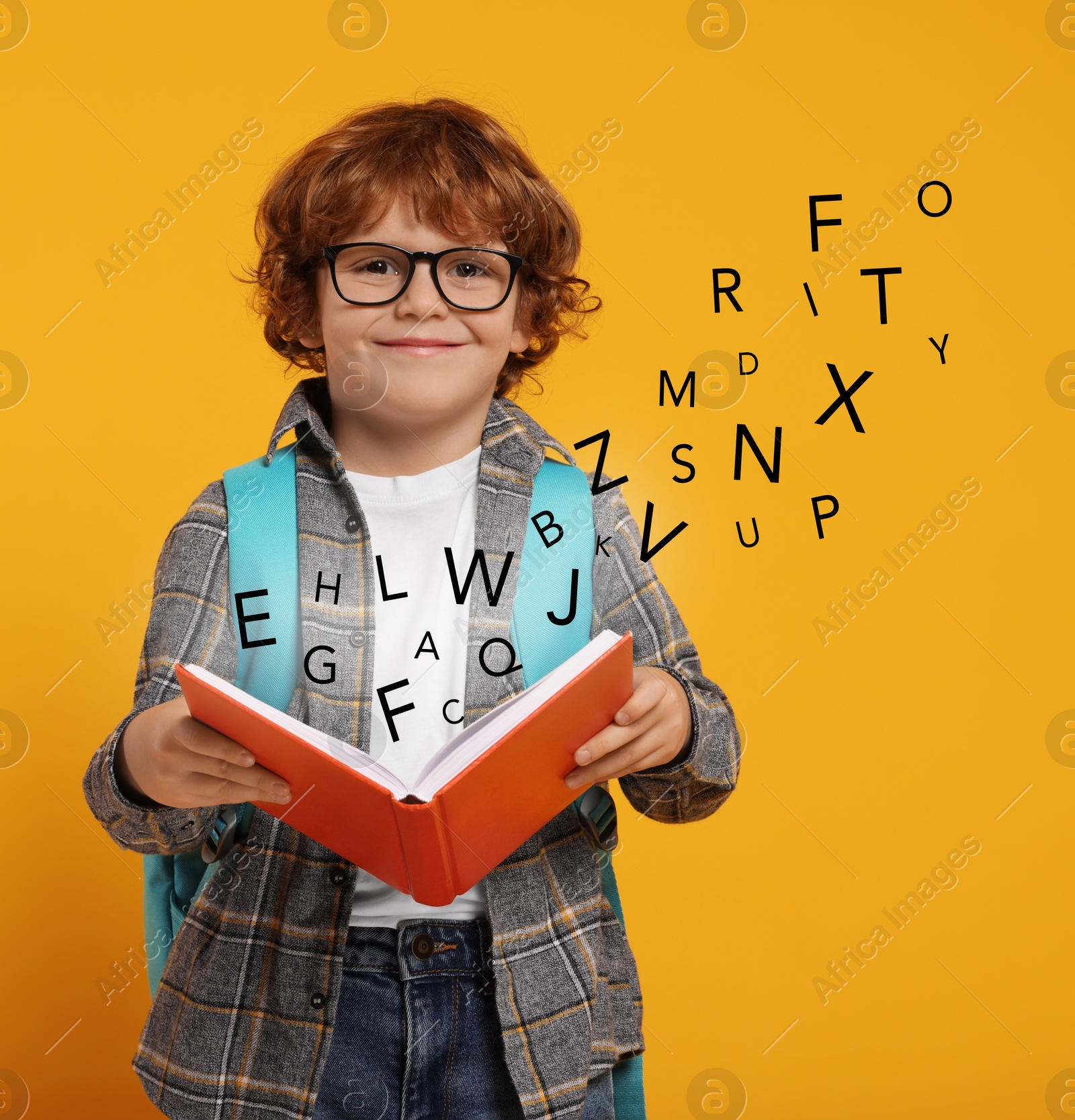 Image of Smiling boy with glasses and book on orange background. Letters flying out of book