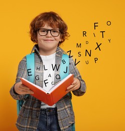 Image of Smiling boy with glasses and book on orange background. Letters flying out of book