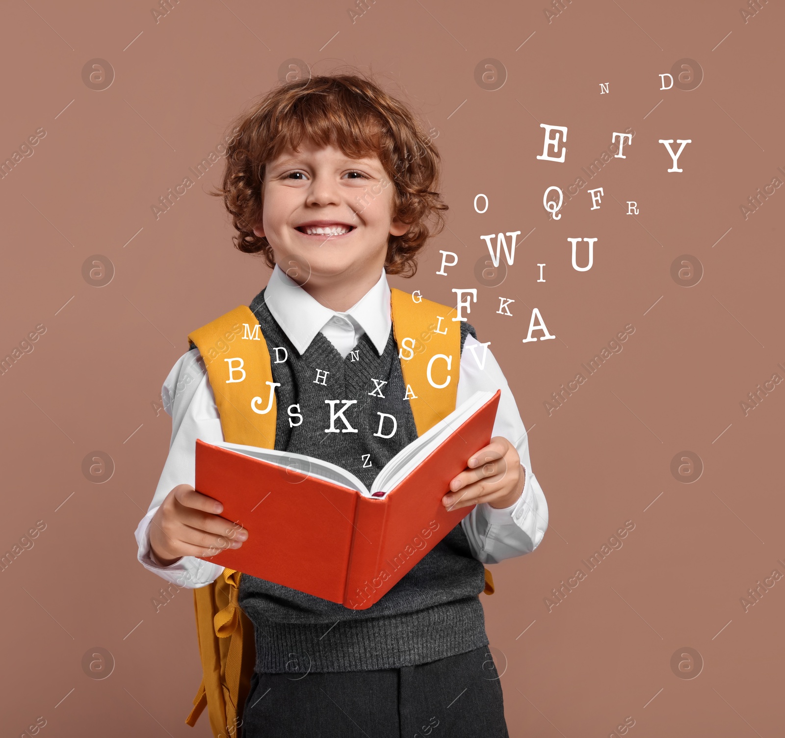 Image of Smiling boy with book on brown background. Letters flying out of book