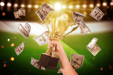 Image of Man holding gold trophy cup in money rain at stadium, closeup