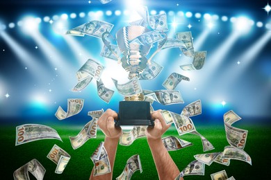 Image of Man holding gold trophy cup in money rain at stadium, closeup