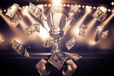 Image of Man holding gold trophy cup in money rain at stadium, closeup. Color toned