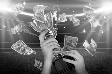 Image of Man holding gold trophy cup in money rain at stadium, closeup. Black-and-white effect