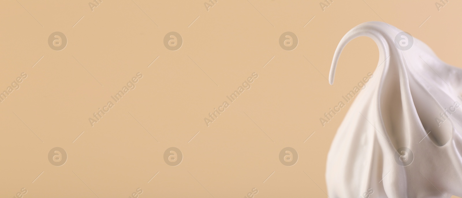 Image of Whisk with beaten cream on dark beige background, closeup. Banner design, space for text