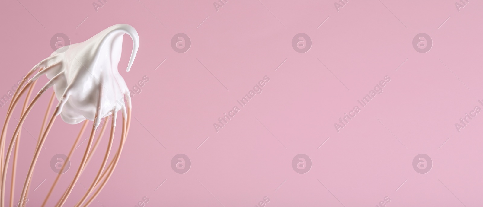 Image of Whisk with beaten cream on pink background, closeup. Banner design, space for text