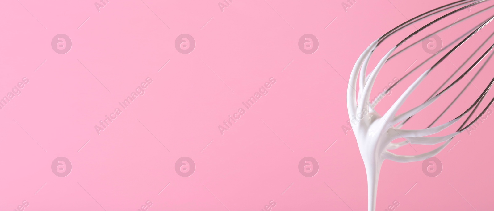 Image of Whisk with beaten cream on pink background, closeup. Banner design, space for text