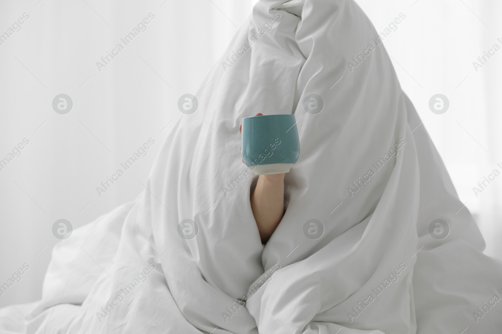 Photo of Woman wrapping in blanket sitting with cup of coffee at home. Good morning