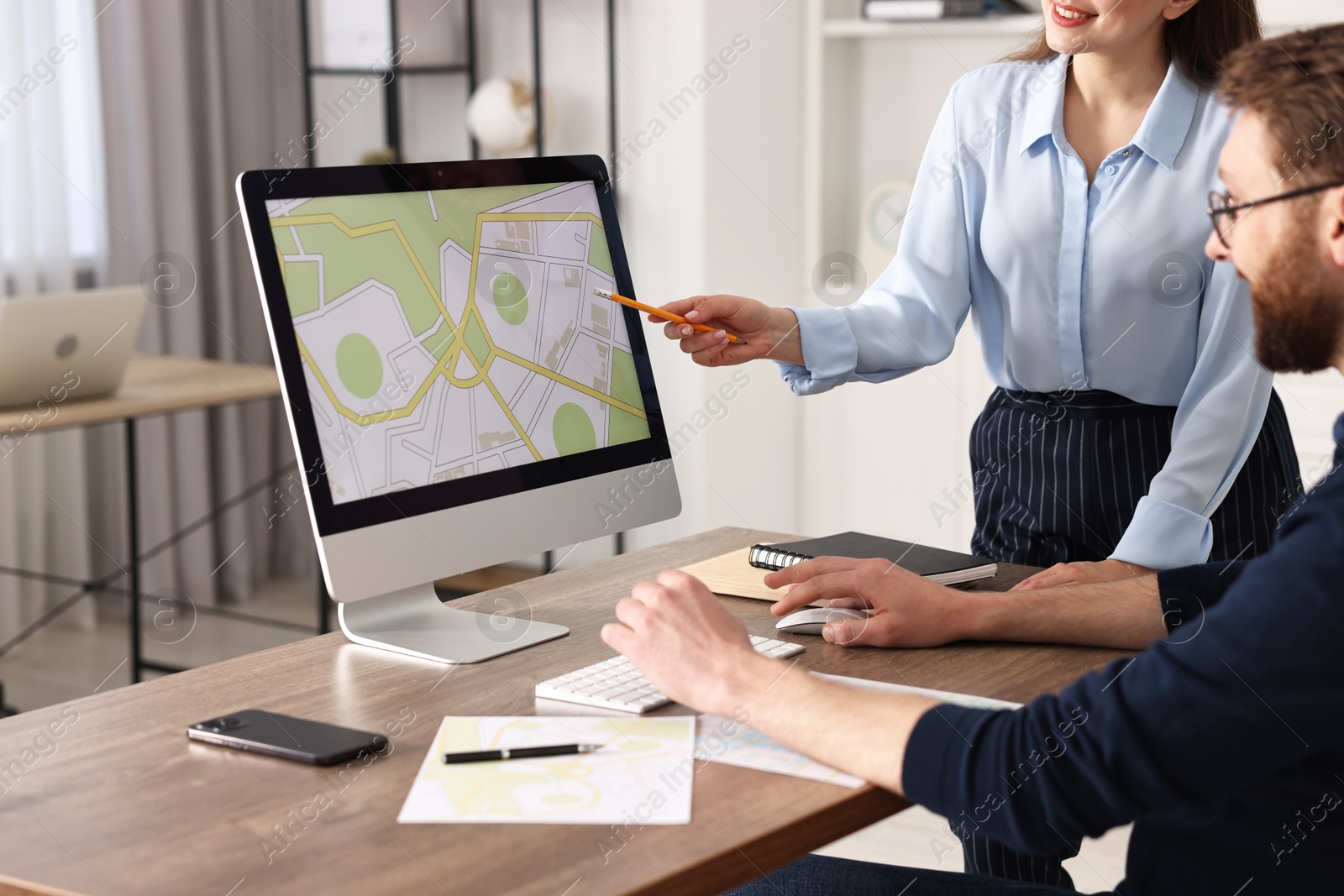 Photo of Cartographers working with cadastral map on computer at table in office