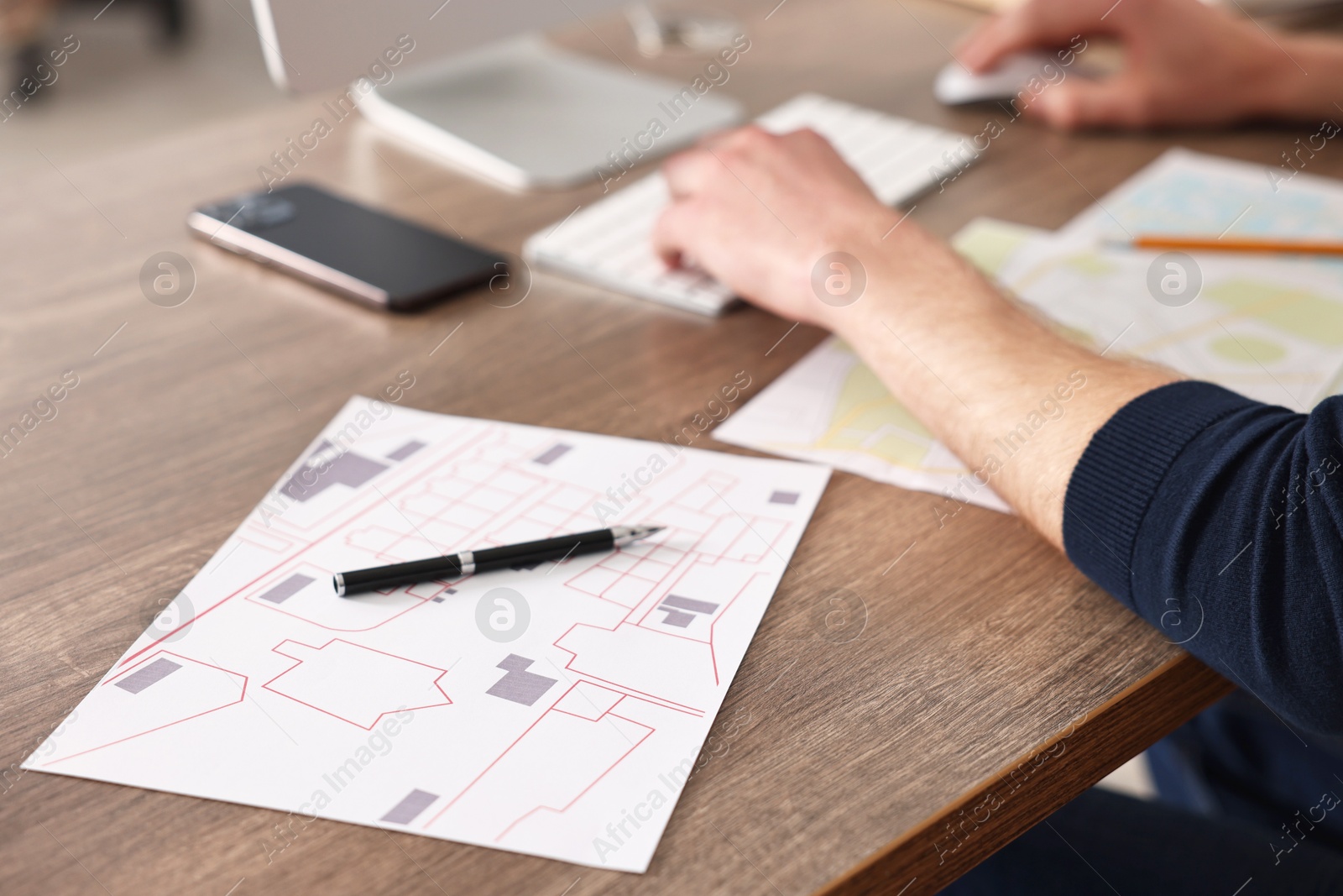 Photo of Cartographer working with cadastral maps at wooden table in office, closeup