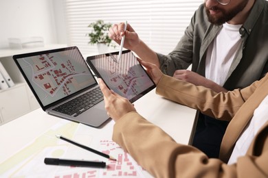 Photo of Cartographers working with cadastral map on tablet at white table in office, closeup