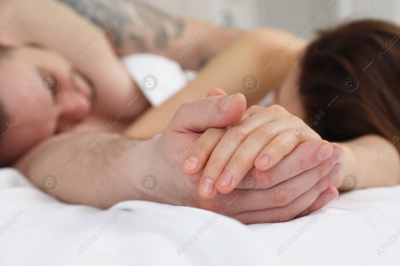 Photo of Lovely couple holding hands in bed, closeup