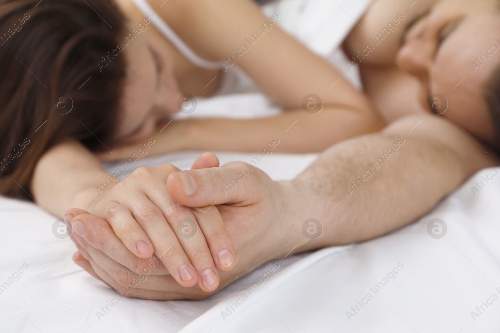 Photo of Lovely couple holding hands in bed, closeup