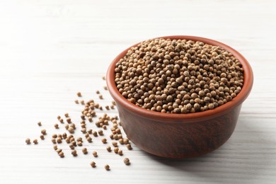 Photo of Dried coriander seeds in bowl on wooden table