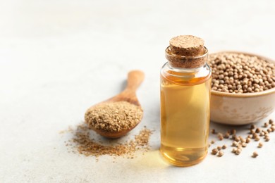 Coriander essential oil, powder and seeds on light grey table