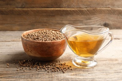 Dried coriander seeds in bowl and oil on wooden table