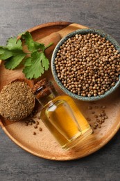 Coriander essential oil, seeds, powder and green leaves on grey table, top view