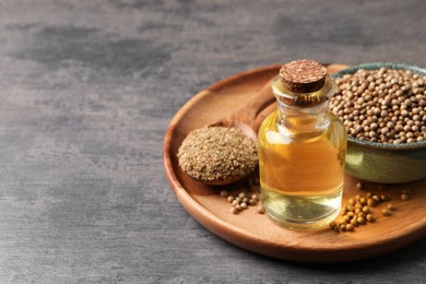 Coriander essential oil, seeds and powder on grey table, space for text