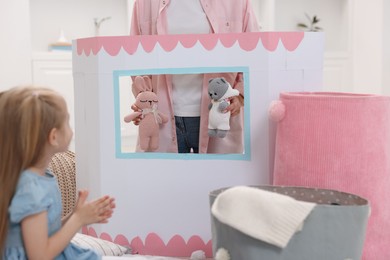 Photo of Puppet theatre. Mother performing show with toys to her daughter at home, closeup