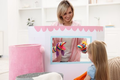 Photo of Puppet theatre. Smiling mother performing show to her daughter at home