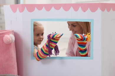 Mother and daughter performing show in puppet theatre at home