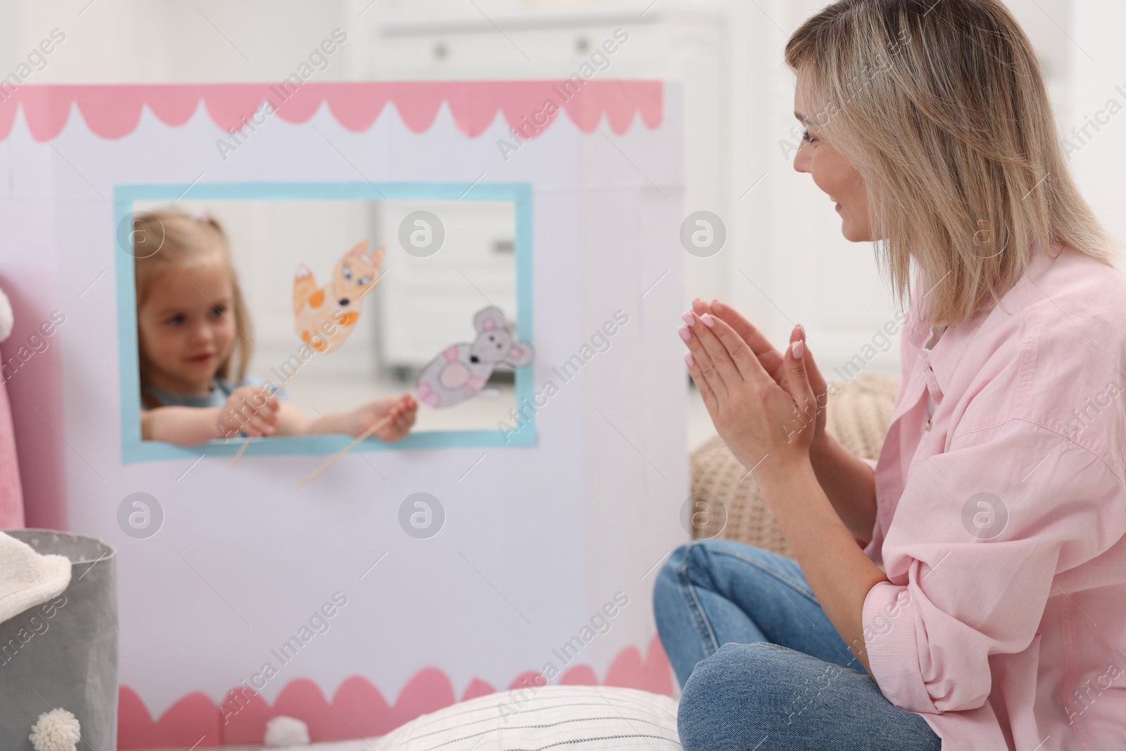 Photo of Puppet theatre. Girl performing show with toy to her mother at home