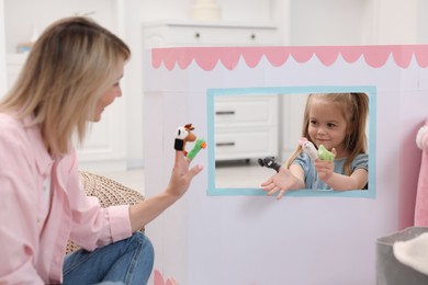 Puppet theatre. Mother and daughter performing show at home