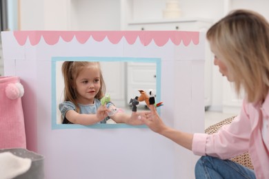 Puppet theatre. Mother and daughter performing show at home